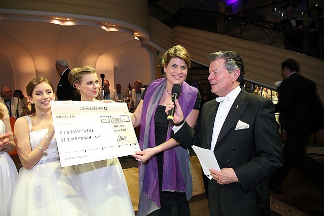 Scheckübergabe Chrysanthemenball 2011 Personen von links: 2 Ballerinen aus dem Kinder-Ballett-Studio Junghanns München, Landtagsabgeordnete Claudia Stamm, Moderator des Chrysanthemenballs Peter A. Machac