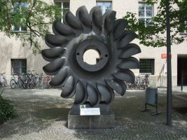 Deutsches Museum Innenhof, Laufrad einer Pelton-Turbine, Baujahr ist 1930, das Laufrad war im Großkraftwerk Vermunt der Vorarlberger Illwerke AG von 1931 bis 1952 in Betrieb. Pelton-Turbinen werden bei geringer Wassermenge aber großen Fallhöhen eingesetzt (über 1000 Höhenmeter). Fallhöhe im Illwerk 700 Meter, Wasserdurchsatz von 4 Kubimeter pro Sekunde, Drehfrequenz 500 min hoch minus 1, Leistung 24,3 MW (33.000PS), Masse 15 Tonnen, Durchmesser 2,5 Meter, Stifter dieser Pelton-Turbine ist die Escher Wyss GmbH Ravensburg, Inventarnummer: 72476, näheres siehe Wikipedia